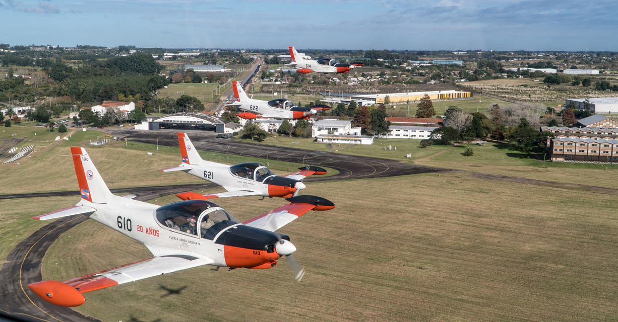 FAU 610 on the foreground with the sentence "20 years" on its side fuselage, leads an echelon left formation of SF-260EUs over the EMA's runway. (EMA)